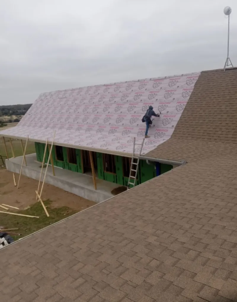 Worker preparing underlayment for a metal roof installation in Larkin